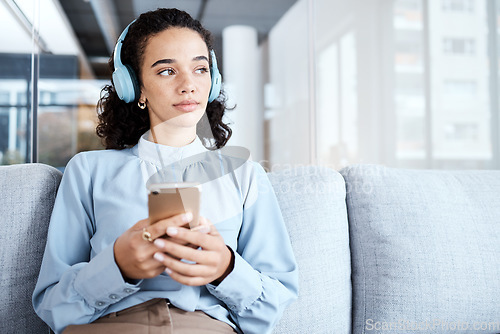 Image of Music headphones, phone and business woman on sofa in office streaming audio. Cellphone, technology and thinking female employee on couch listening to podcast, radio or sound with mobile smartphone.