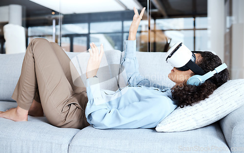 Image of Virtual reality, metaverse and gamer with a black woman on a sofa in the living room of her home. AI, 3D and VR with a young female gaming using a headset to access cyberspace for a video game