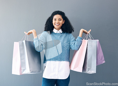 Image of Shopping, black woman and portrait of a happy customer with bags after boutique or shop sale. Isolated, gray background and female smile in a studio holding a bag with discount market product