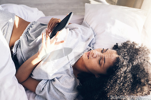Image of Black woman, bed and phone in home bedroom for social media, texting or internet browsing in the morning. Technology, relax and female with mobile smartphone for web scrolling or networking in house.