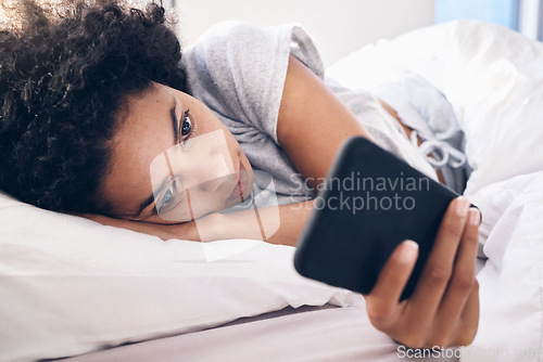 Image of Phone, social media and a black woman lying in bed in the morning after waking up on the weekend. Mobile, communication and relax with an attractive young female resting in her bedroom in a house