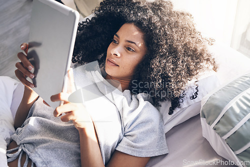 Image of Tablet, black woman and relax in bed in bedroom for social media, texting or internet browsing in the morning. Technology, home and female with digital touchscreen for web scrolling after waking up.