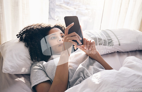 Image of Phone, black woman and typing in home bedroom for social media, texting or internet browsing in the morning. Technology, bed relax and female with mobile smartphone for web scrolling or networking.