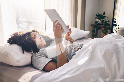 Image of Relax, tablet and black woman in bed in bedroom for social media, texting or internet browsing in the morning. Technology, home and female with digital touchscreen for web scrolling after waking up.