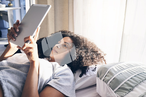 Image of Tablet, black woman and relax in bed in bedroom for social media, texting or internet browsing in the morning. Technology, home and female with digital touchscreen for web scrolling after waking up.