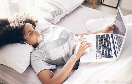 Image of Music earphones, woman and laptop in bed in bedroom for social media or internet browsing in the morning. Technology, relax or black female with computer for streaming podcast, audio or radio in home