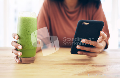 Image of Hands, glass and phone with a black woman in the kitchen of her home for health, weight loss or nutrition. Mobile, smoothie and wellness with a female posting a status update on social media