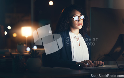 Image of Serious, night and business black woman on computer for planning, project management and research. Dark office, overtime and female worker focus working on strategy, reading website and typing email