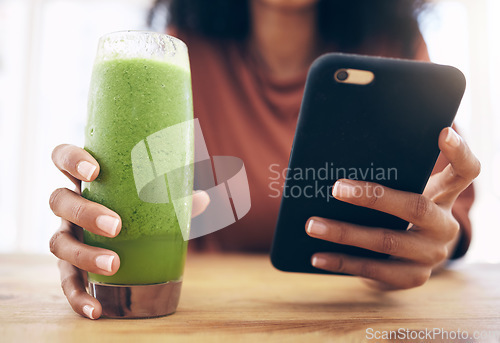 Image of Hands, smoothie and phone with a black woman in the kitchen of her home for health, weight loss or nutrition. Mobile, glass and wellness with a female posting a status update on social media