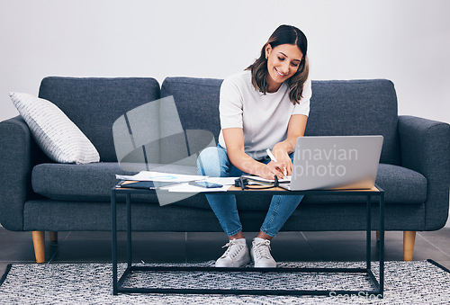 Image of Woman, laptop and writing notes on living room sofa in remote work or studying on table at home. Female freelancer working with smile for planning, strategy or notebook by computer sitting on couch