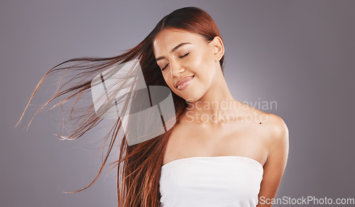 Image of Happy, hair and hairstyle by woman with smooth, glow and healthy skincare isolated in a studio gray background. Young, skin and natural model smile due to keratin treatment for haircare