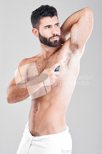 Image of Deodorant, spray and man in studio grooming for hygiene, fresh scent or sweating smell. Male model spraying armpit of body odor, beauty cosmetics and cleaning skincare of bottle product on background