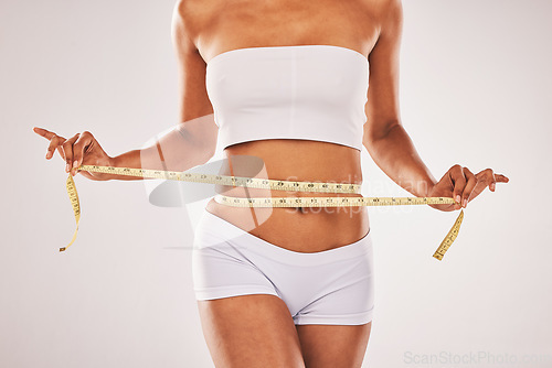 Image of Weight, loose and woman with tape for stomach isolated on a grey studio background. Diet, health and girl measuring her waist for slim shape, motivation and belly while standing on a backdrop