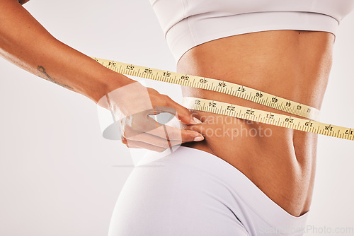 Image of Weight, fat and woman with tape for stomach isolated on a grey studio background. Insecurity, health and girl measuring her body for slim shape, cellulite and belly while standing on a backdrop