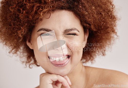 Image of Black woman face, wink and beauty with smile, funny facial expression with skincare and natural hair on studio background. Healthy skin, cosmetics and teeth, dermatology and wellness in portrait