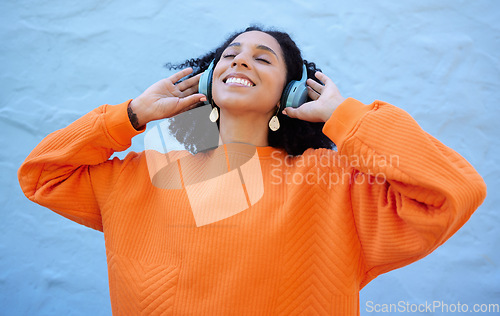 Image of Black woman, headphones and listen to music, freedom to relax with wellness and audio streaming. Happiness, care free with radio or podcast, mindset and peace of mind with playlist on blue background