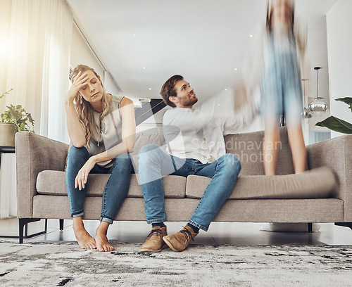 Image of Family life stress, parents and child, chaos at home and energy, motion blur and burnout headache. Kid jump on couch, woman has migraine and man calming girl, hyperactive with ADHD and mental health