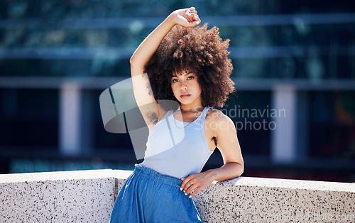 Image of Portrait, fashion and trendy with a black woman in the city on a bridge, looking relaxed during summer. Street, style or urban and a natural young female posing outside with an afro hairstyle