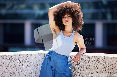 Image of Portrait, fashion and armpit hair with a black woman in the city on a bridge, looking relaxed during summer. Street, style or urban and a natural young female feminist outside with an afro hairstyle