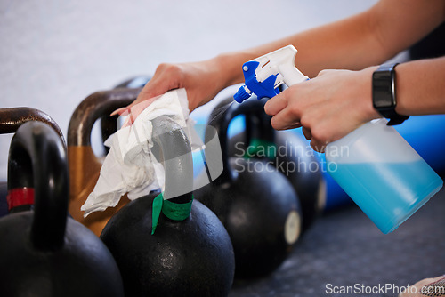 Image of Gym, hygiene and hands cleaning kettlebell with cloth and spray bottle, dirt and germs at fitness studio. Janitor, cleaner or caretaker at sports club washing dust and bacteria from workout equipment