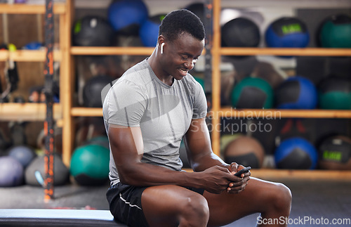 Image of Phone, fitness and black man in gym training, workout or exercise social media or internet search for health tips. Bodybuilder, sports person listening to music or typing on smartphone chat or mobile