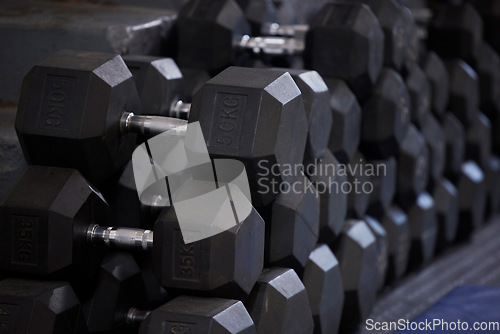 Image of Fitness, workout and dumbbells in empty gym for exercise, bodybuilding development and sports training club. Background zoom of heavy steel weights, equipment and iron for lifting in wellness studio