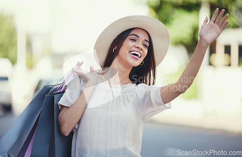 Image of Woman, shopping bags and hand signal in the city waiting on the street for transport, lift or travel. Happy female shopper waving hands carrying gifts in discount, deal or sale for traveling in town