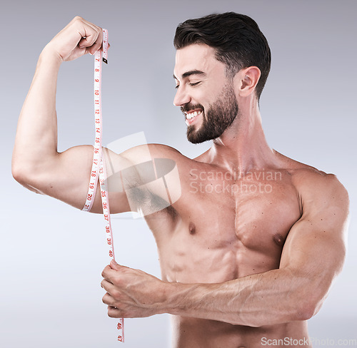 Image of Fitness, goals or strong man with tape measure for biceps after body exercise on studio background. Happy bodybuilder measuring arm for training, workout or muscle growth progress, results or target