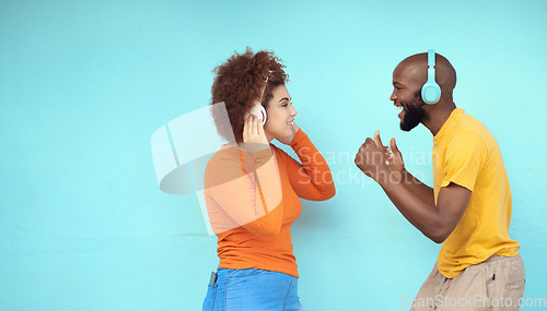 Image of Couple of friends in headphones isolated on a blue background for dancing, celebration and listening to music. Black woman with dance partner or people with audio, podcast and gen z technology mockup