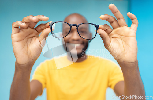 Image of Hands, glasses and vision with a black man in studio on a blue background for prescription frame lenses. Spectacles, eyesight and eyewear with a male indoor to promote new round frames for seeing