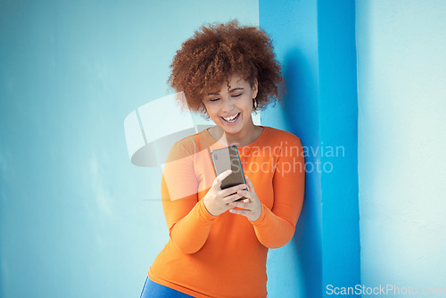 Image of Black woman, cellphone and laughing on mobile on blue wall of social media, technology or network. Happy young girl typing on smartphone of connection, reading funny notification and meme post online