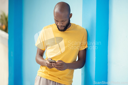 Image of Thinking black man, phone or typing on blue background on social media, internet app or reading news blog. Fashion clothes, person or student on mobile technology with fashion clothes ideas or vision