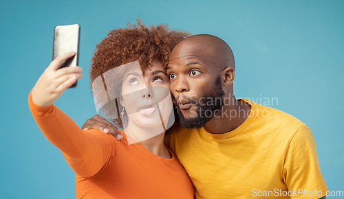 Image of Couple, hug and funny faces selfie on blue background, isolated mockup or wall mock up for social media. Comic, goofy and silly black man and woman on photography tech for interracial profile picture