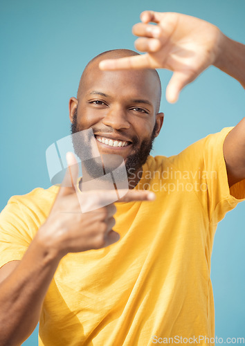 Image of Hands, frame and portrait of black man on blue background for profile picture. Face, happy guy and finger framing for perspective, selfie and vision of happiness, smile and photography sign in studio