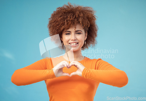 Image of Heart, hand and portrait of woman in studio for love, happy and smile against blue background space. Emoji, hands and face of girl model relax with finger, frame and loving message, gesture and sign