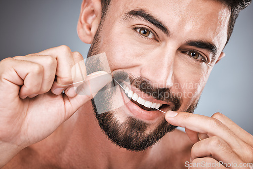 Image of Floss, cleaning teeth and portrait of man in studio for beauty, healthy body and hygiene on background. Male model, tooth flossing and mouth for facial smile, fresh breath and happy dental wellness