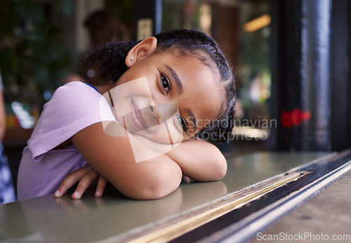 Image of Portrait, cute and adorable girl at a restaurant, cafe and coffee shop with a smile and happy waiting. Kid, child and young person sitting alone in happiness on a weekend in the city or town