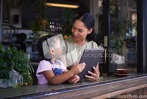 Image of Streaming, cafe and woman and girl with a tablet talking while on social media, online and app at a coffee shop. Kid, daughter and child with mother on the internet for browsing the web or website