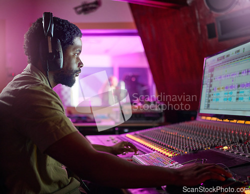 Image of Black man, studio recording and music job in night with headphones, computer or focus by mixing console. Sound engineer, producer or audio technology for professional production of hit song for radio