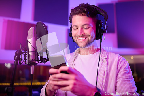Image of Man, phone and smile in music studio chatting, social media or podcast post at the workplace. Happy male auto tuner smiling on smartphone for networking, sound track or listening in sound proof room