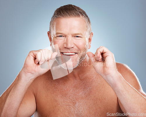 Image of Floss, portrait and man with oral hygiene to clean mouth, wellness and guy against blue studio background. Male, gentleman and string for fresh breath, dental health and morning routine or grooming