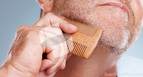 Image of Grooming, hair care and man brush beard for wellness, healthy skin and hygiene on blue background. Salon aesthetic, cleaning and face zoom of male with barber comb for facial, skincare and beauty