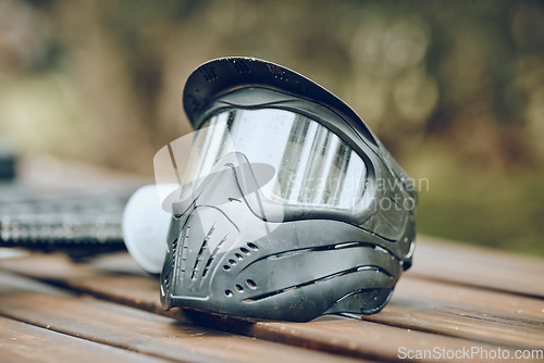Image of Helmet, paintball and sports with equipment on a table outdoor for military or army training on a battlefield. Safety, exercise and mask with combat accessories on a wooden surface for war simulation