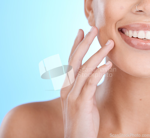 Image of Hands, face and touching skin with a model woman in studio on a blue background for beauty or skincare. Hand, touch and facial with a young female indoor to promote an antiaging skin product