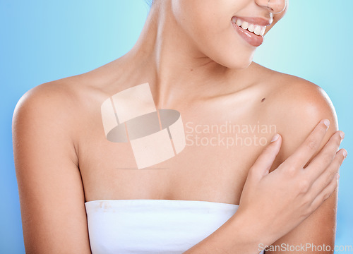 Image of Woman, hands and smile for skincare, cosmetics or spa treatment against a blue studio background. Hand of happy female touching shoulder and smiling in beauty for soft smooth skin, self love or care