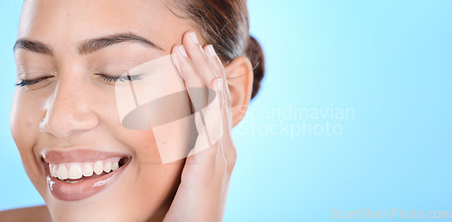 Image of Woman, skincare and hands on face in studio for makeup, wellness or gentle cleaning on blue background. Face, beauty and girl skin model relax in luxury, facial and cosmetic treatment while isolated