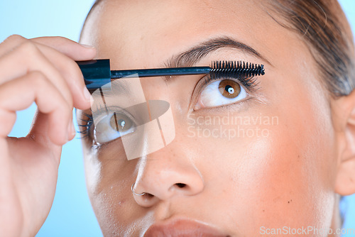 Image of Makeup, mascara and eyelashes with a model black woman in studio on a blue background for beauty. Eyes, cosmetics and apply with an attractive young female indoor to promote a cosmetic product