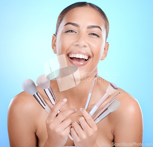 Image of Black woman, studio portrait and smile for makeup brushes in hands for face, natural beauty and blue background. Happy gen z model, cosmetics skincare and facial glow aesthetic for foundation product