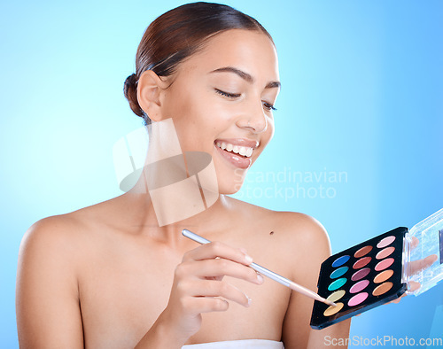 Image of Makeup, palette and woman isolated on blue background for youth, beauty or skincare product promotion. Model, artist or creative person, cosmetics eyeshadow and color choice for face in studio mockup