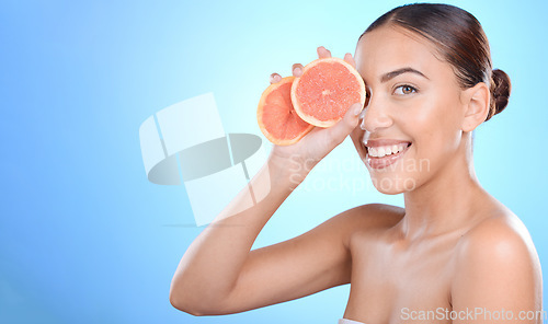 Image of Skincare, portrait and woman with grapefruit in studio for cosmetics, wellness and treatment on blue background. Face, beauty and girl model on fruit, product and luxury cleaning, grooming or hygiene